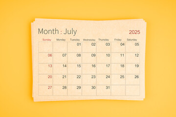 July 2025 calendar from brown recycle paper on yellow background.