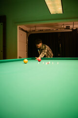 Player focuses while shooting on green pool table