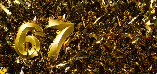 Golden candles number 67 on gold tinsel background. Celebration sixty-seventh birthday. Concept of celebrating birthday.