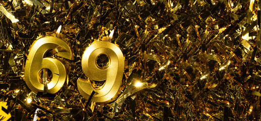 Golden candles number 69 on gold tinsel background. Celebration sixty-ninth birthday. Concept of...