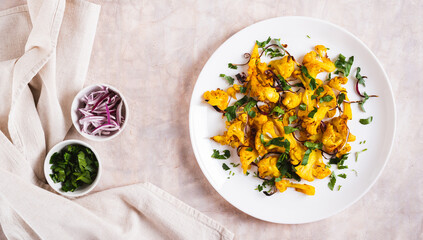 Baked spicy cauliflower with onions and parsley on a plate on the table top view web banner