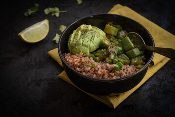 Buckwheat and okra  and peas bowl, avocado, lime, served on dark background