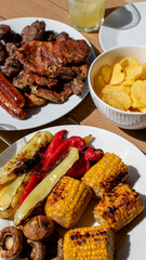 Grilled meats and vegetables with chips on outdoor table, ideal for summer barbecue or Fourth of July celebration