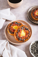Egg with tomato and sesame seeds baked in bagels on a plate on the table vertical view