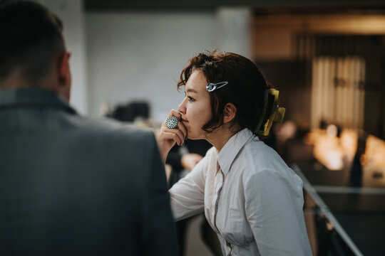 A candid moment of two business professionals deep in conversation, reflecting contemporary office work culture. The image captures a relaxed yet professional atmosphere.