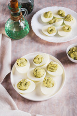 Avocado deviled eggs for appetizer on plate on table vertical view