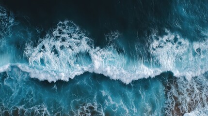 Fototapeta premium Aerial view of ocean waves with white foam crashing on sandy beach, powerful natural beauty.