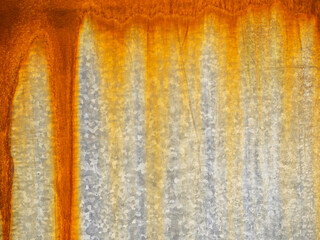 A rusty metal surface with a yellowish-orange hue. The surface appears to be weathered and worn, giving it a sense of age and history