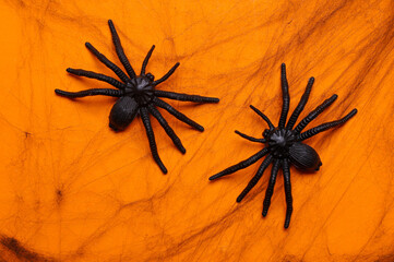 Black decorative web with spiders on orange background. Halloween decor. Flat lay