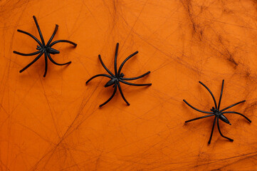 Black decorative web with spiders on orange background. Halloween decor.