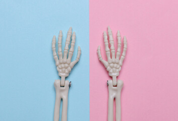 Decorative skeleton hands on purple background. Halloween still life. Top view