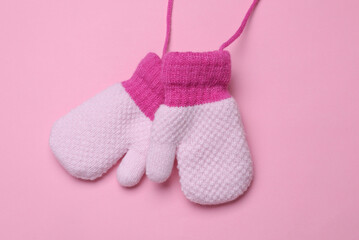 Children's knitted mittens on strings, pink background