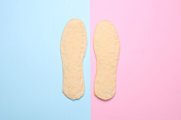 Pair of wool insoles on a pink blue background