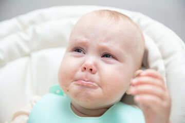 Crying baby doesn't want to eat at the feeding table