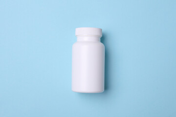 White plastic pill bottle on blue background. Mockup for design
