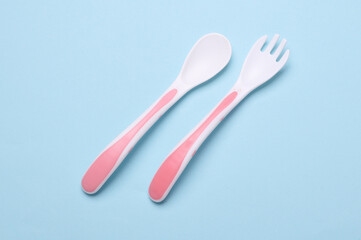 Plastic fork and spoon for feeding baby on blue background