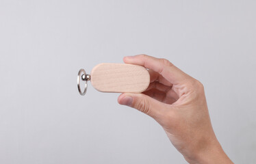 Female hand holding wooden keychain on grey background