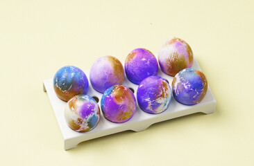 Colored Easter eggs in a tray, yellow background