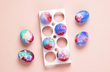 Colored Easter eggs in tray, pink background. Top view