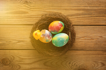 Multicolored Easter eggs in nest on wooden table. Top view