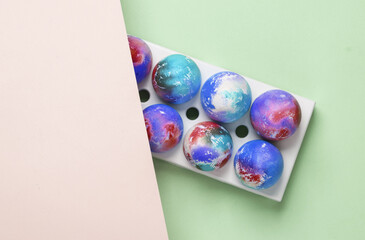 Colored Easter eggs in tray on pastel background.