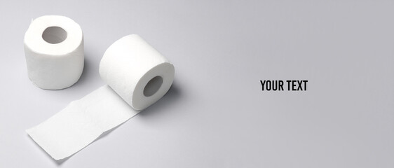 Two rolls of white toilet paper on a blue background with a shadow. Copy space