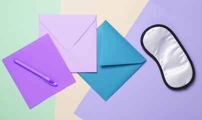Colored envelopes and a sleeping mask on a pastel backgroundя. Top view