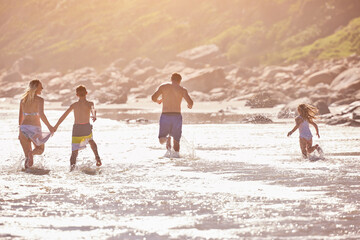 Water, kids and parents running on beach for fun, travel holiday or bonding together on tropical adventure. Waves, energy and family playing on island vacation with ocean, splash and summer from back