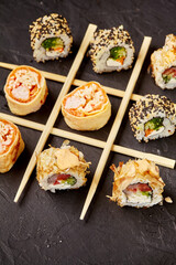 Various sushi rolls forming tic-tac-toe game on dark background
