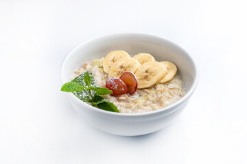 Oatmeal porridge with banana and grape in bowl on white background