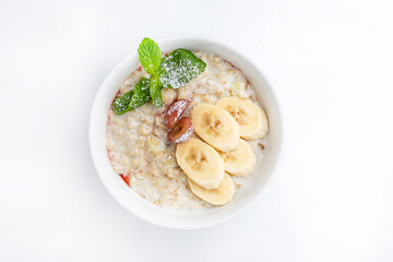 Oatmeal porridge with banana and grape in bowl on white background