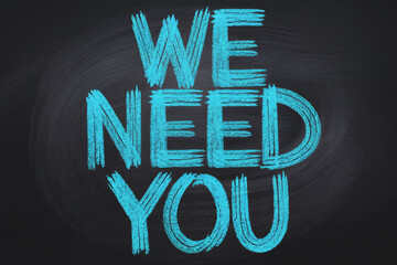 Chalkboard with teal "We Need You" message, hand-drawn style, conveying a sense of urgency and recruitment