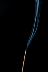 Burning incense with smoke on a black background.