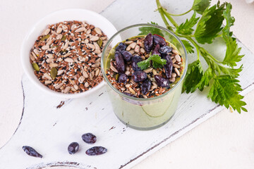 Healthy eating, lifestyle, veganism, alkaline diet, vegetarian concept. Green smoothies from nettle and yogurt, with honey, bran, seed mix and honeysuckle. Garnished with a mint leaf