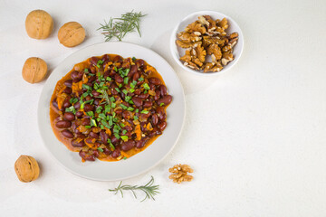 Red beans in tomato sauce with green onions and walnuts. Lenten vegetarian food. Copy space