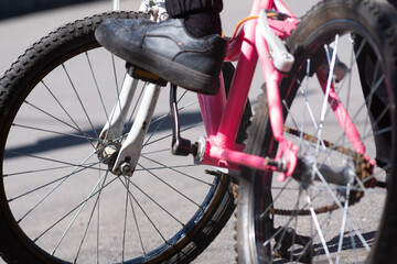 Close-up of a teenager s sneaker pressing the pedal of a bicycle. Visible wheels, foot, and pedals. Concept of active lifestyle, cycling, motion, and outdoor activity.
