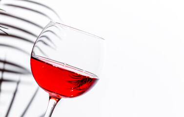 Non-alcoholic, alcohol fries,  pink rose wine grenache in glass with bottle. White background, palm leaves shadows, hard light