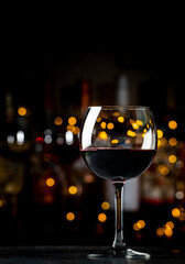 Italian dry red wine chianti glass and wine bottles on dark bar background with lights