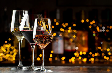 Wine glasses set. Red, white, rose wines on dark background with bottles. Wine bar, shop, tasting
