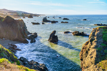 Coastal cliffs along California's Highway 1 in Northern California. Rugged ocean rocks, crashing waves, and a colorful sky create a breathtaking Pacific Coast landscape