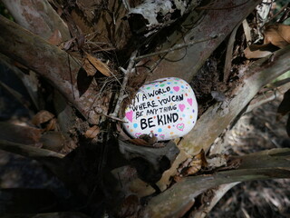 Old palm tree trunk with be kind kindness rock