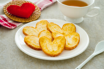 Crispy heart or butterfly puff pastry cookie and cup of tea