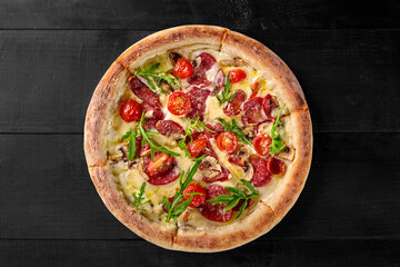 Round pizza with salami, mushrooms, arugula and cherry tomatoes is showing its delicious look