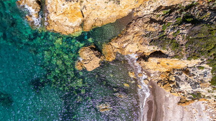 Top down view of the bright turquoise sea hitting the rocky cliffs on the Corsican coast offering a breathtaking natural background