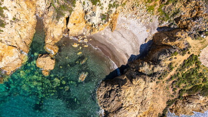 Aerial view of turquoise sea along the Corsican coast with rugged rocky cliffs and waves crashing creating a stunning natural seascape