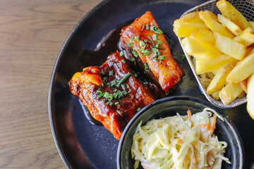 Barbecue pork ribs served with crispy french fries and fresh coleslaw salad tasty lunch plate juicy meat with sauce delicious meal restaurant serving american cuisine background.