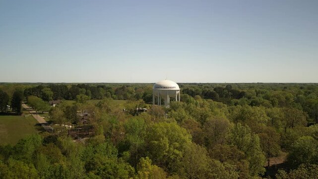 Aerial zoom out and pan on Corinthe Mississippi water tower and trees in springtime