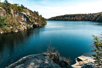 Kerhonkson, NY - US - Apr 23, 2025 Lake Awosting glistens under a clear sky, bordered by rugged cliffs and forested hillsides in Minnewaska State Park—a serene gem perfect for nature lovers.