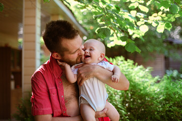 Fototapeta premium Young father spending time with baby son outdoors. Lifestyle photo of parent playing with laughing toddler child in nature. Family value, father and son, father's day. Selective focus.