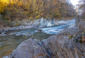 A cool autumn morning on a mountain river, the first rays of the sun illuminate a forest covered with frost